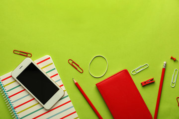 Composition with different school stationery and mobile phone on color background