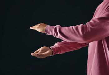 Young man holding something on dark background