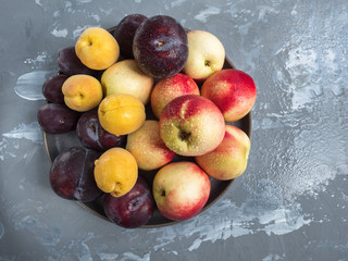 ripe nectarines and red plums on a round platter