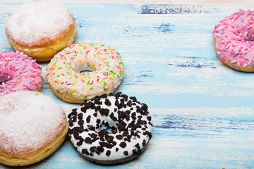 Traditional donuts on white wooden background.  Tasty doughnuts with icing and powdered sugar, copy space