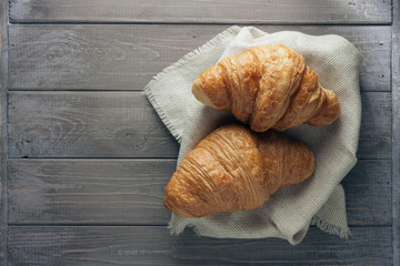 Fototapeta na wymiar Two freshly baked croissants on old wooden table. Top view with copy space