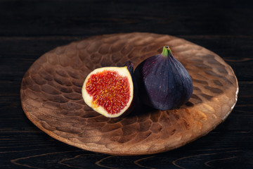 A few figs on a plate on an black wooden background. Healing Fruit