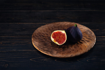 A few figs on a plate on an black wooden background. Healing Fruit
