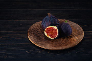 A few figs on a plate on an black wooden background. Healing Fruit