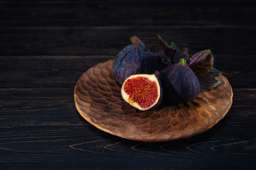 A few figs on a plate on an black wooden background. Healing Fruit