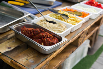 products for cooking falafel in dishes on a wooden table. Street food ready to serve on a food stall.