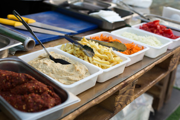 products for cooking falafel in dishes on a wooden table. Street food ready to serve on a food stall.