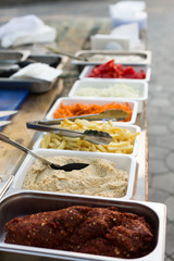 products for cooking falafel in dishes on a wooden table. Street food ready to serve on a food stall.