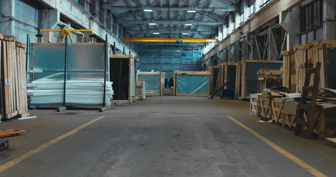 FIXED unrecognizable people working in a large warehouse, worker moving crane beam with a remote controller. 4K UHD