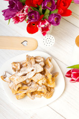 Faworki - Traditional Polish cookies served at Fat Thursday.  Cookies and tulip bouquet on white wooden background
