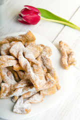 Faworki - Traditional Polish cookies served at Fat Thursday.  Cookies and tulip bouquet on white wooden background