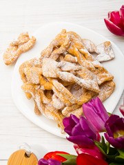 Faworki - Traditional Polish cookies served at Fat Thursday.  Cookies and tulip bouquet on white wooden background