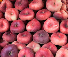 Fresh donut peaches for sale at a market.  Flat or saturn peaches background.