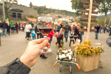 Wine in glass and tourist tasting it at annual city festival Tbilisoba with crowd of people around....