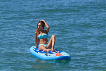 Woman relaxing on a SUP boarding in the sea. Healthy lifestyle in harmony with nature.