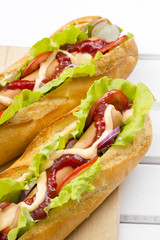 domowe hot dogi na białym drewnianym tle.