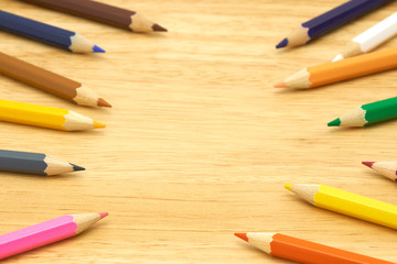 Obraz premium Colorful wooden pencils surround a circle on a wood background. Make a center Can be used as background or fill in text with copy spaces.