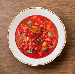 Traditional Russian borscht in a soup plate on a wooden table