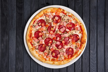 Top view of pizza with sausage, ham and tomato