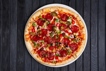 Top view of pizza with chili jalapeno, bell pepper, sausage and onion