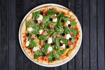 Top view of pizza with ham, feta cheese, anchovy and lettuce salad