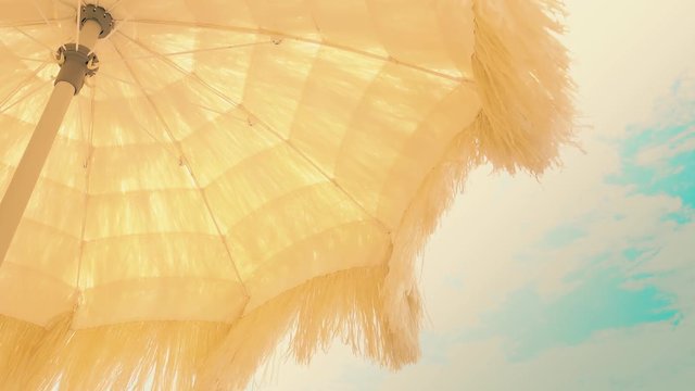 Yellow beach umbrella with waving fringe against the sky