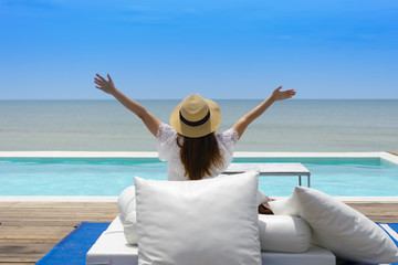 Woman tourist is taken vacation holiday and sitting at the pool on beach side in Thailand.