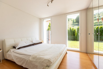 Fototapeta na wymiar Elegant double bedroom with windows to the garden