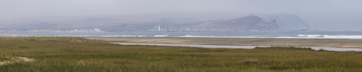 Arica city skyline from Lluta river wetlands with the Pacific Ocean crashing the beach and the...