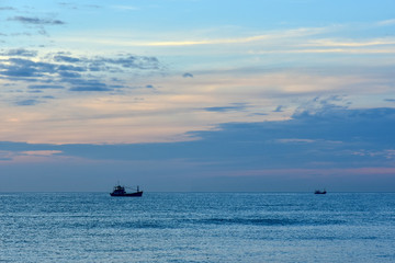 Small silhouette of a fishing boat against a sunset background