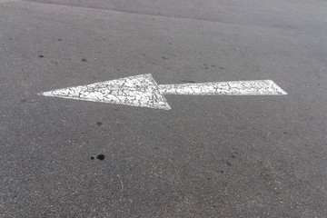 A close up view of a white painted road arrow showing direction of traffic