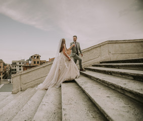 Bride and groom walking outdoors at Spagna Square and Trinita' dei Monti in Rome, Italy