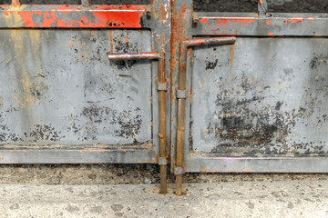 Old scratched, metal gate with vertical lock. Metal bolt on the old-fashioned door.