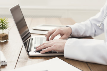 Closeup of doctor hands on laptop keyboard