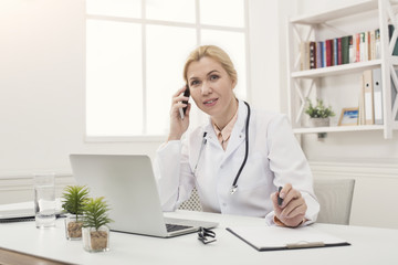 Attractive doctor talking on phone with patient