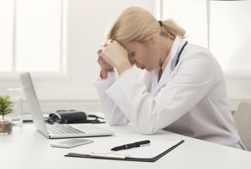 Obraz na płótnie Canvas Tired doctor sitting at workplace in hospital