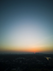 Aerial shot of a soft orange glowing sunset against a cloudless blue sky