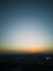 Aerial shot of a soft orange glowing sunset against a cloudless blue sky
