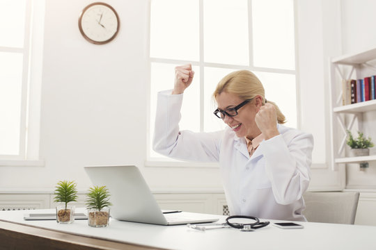 Excited Doctor In Glasses Sitting At Desktop