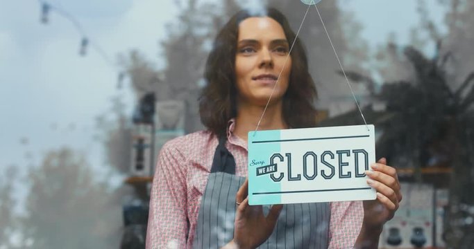 CU Caucasian female turning sign from closed to open on the entrance door or window of her small cafe. Small business concept. 4K UHD 60 FPS SLOW MOTION