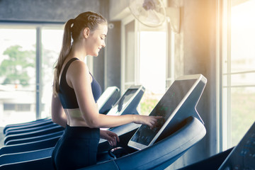 Young woman running on treadmill in the fitness gym.
