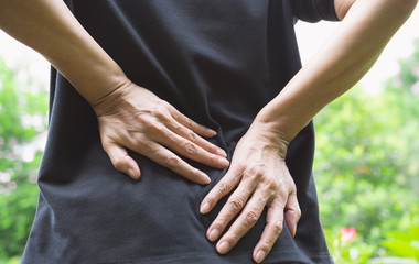 closeup hands of woman touching her back pain in healthy concept on nature background.