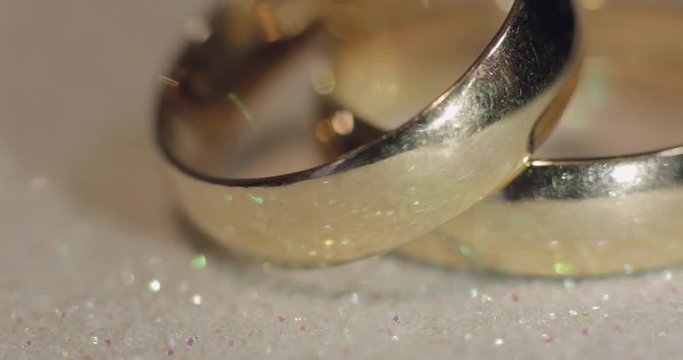 Wedding rings lying on shiny surface shining with light close up macro