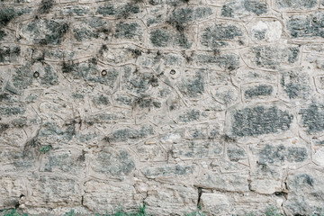 Gray stone wall with black spots . Stones with different shapes