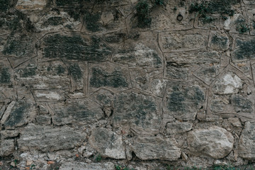 Dark gray stone wall with black spots . Stones with different shapes