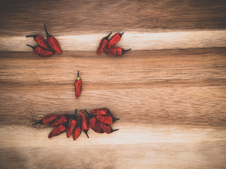Chilies in the shape of a scary halloween face on wooden board