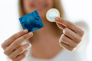 Smiling young woman showing condom ready to use for safe sex over white background.
