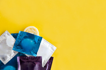 Multi colored condoms over yellow background.