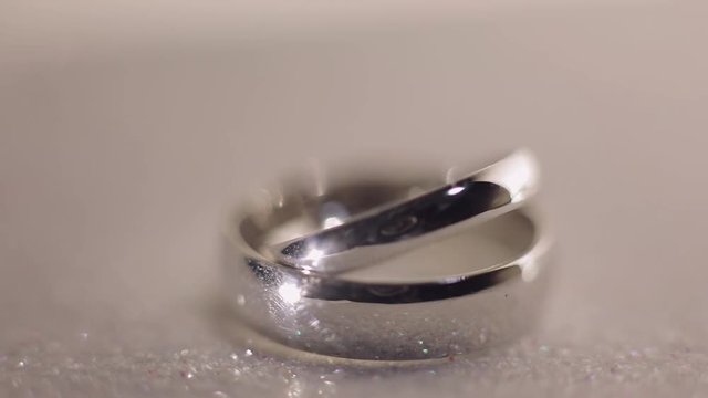 Wedding rings lying on shiny surface shining with light close up macro