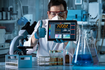 Researcher with thumb up and holding digital tablet with screen of results of dna analysis /...